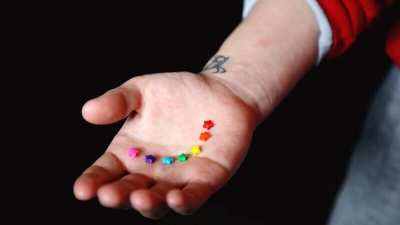 Rainbow colored stars on a person's hand